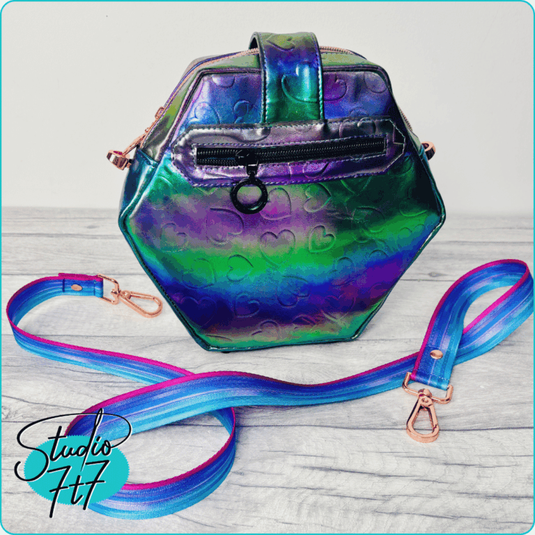 Back view of rainbow holographic heart-embossed hexagon cross body bag showing exterior zip pocket and striped strap – The Hexelle bag sewing pattern by Studio7t7